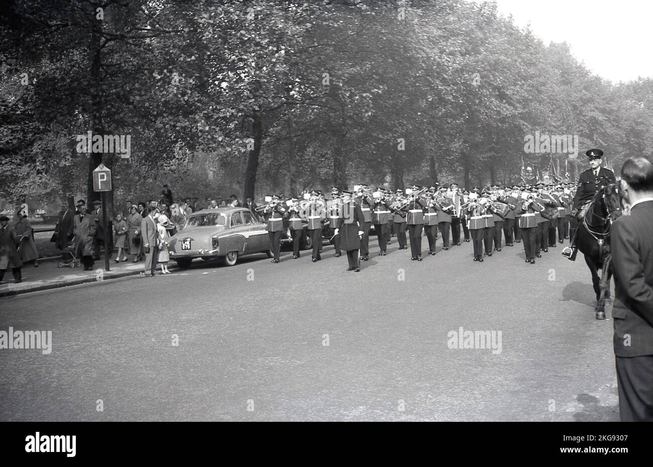 1950s, storico, un poliziotto a cavallo di fronte a una band che gioca mentre camminano lungo una strada, forse l'Esercito della salvezza, che conduce una marcia di ex-servicemen e membri sindacali, Parliament Hill, Westminster, Londra, Inghilterra, REGNO UNITO. Foto Stock