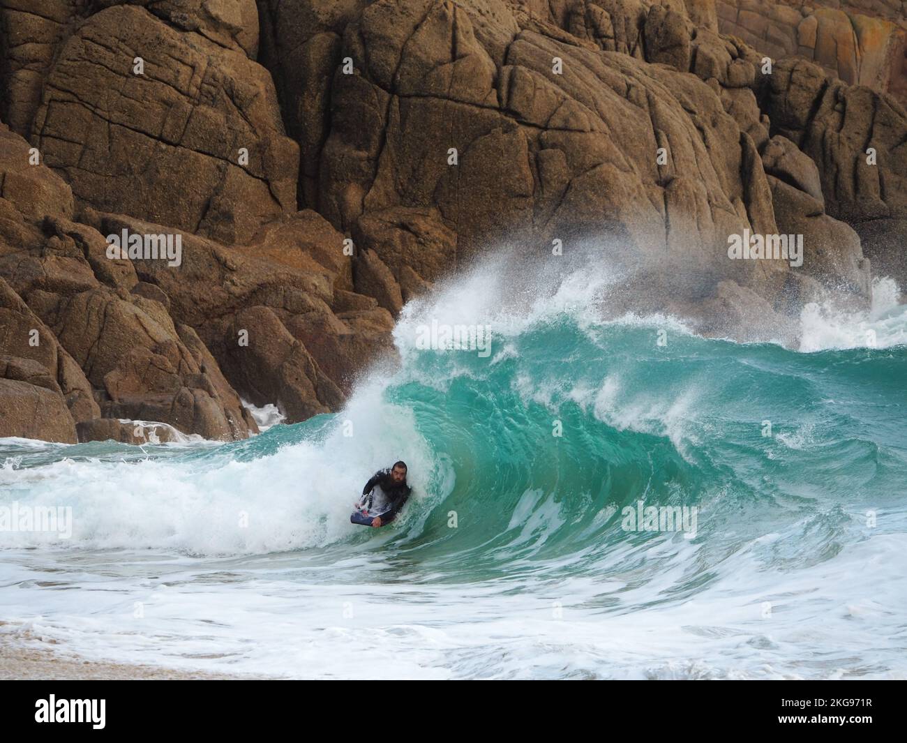 Surfista a Porthcurno, Cornovaglia Foto Stock