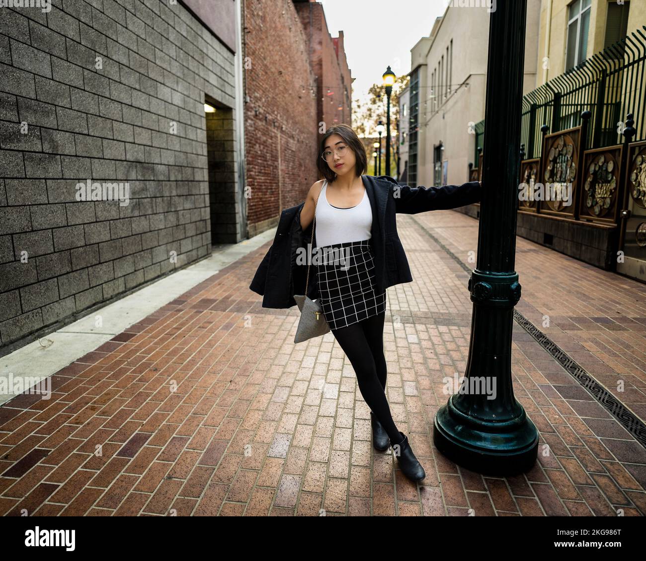 Joyful giovane donna che oscilla su un palo della lampada | Abbigliamento casual di affari Foto Stock