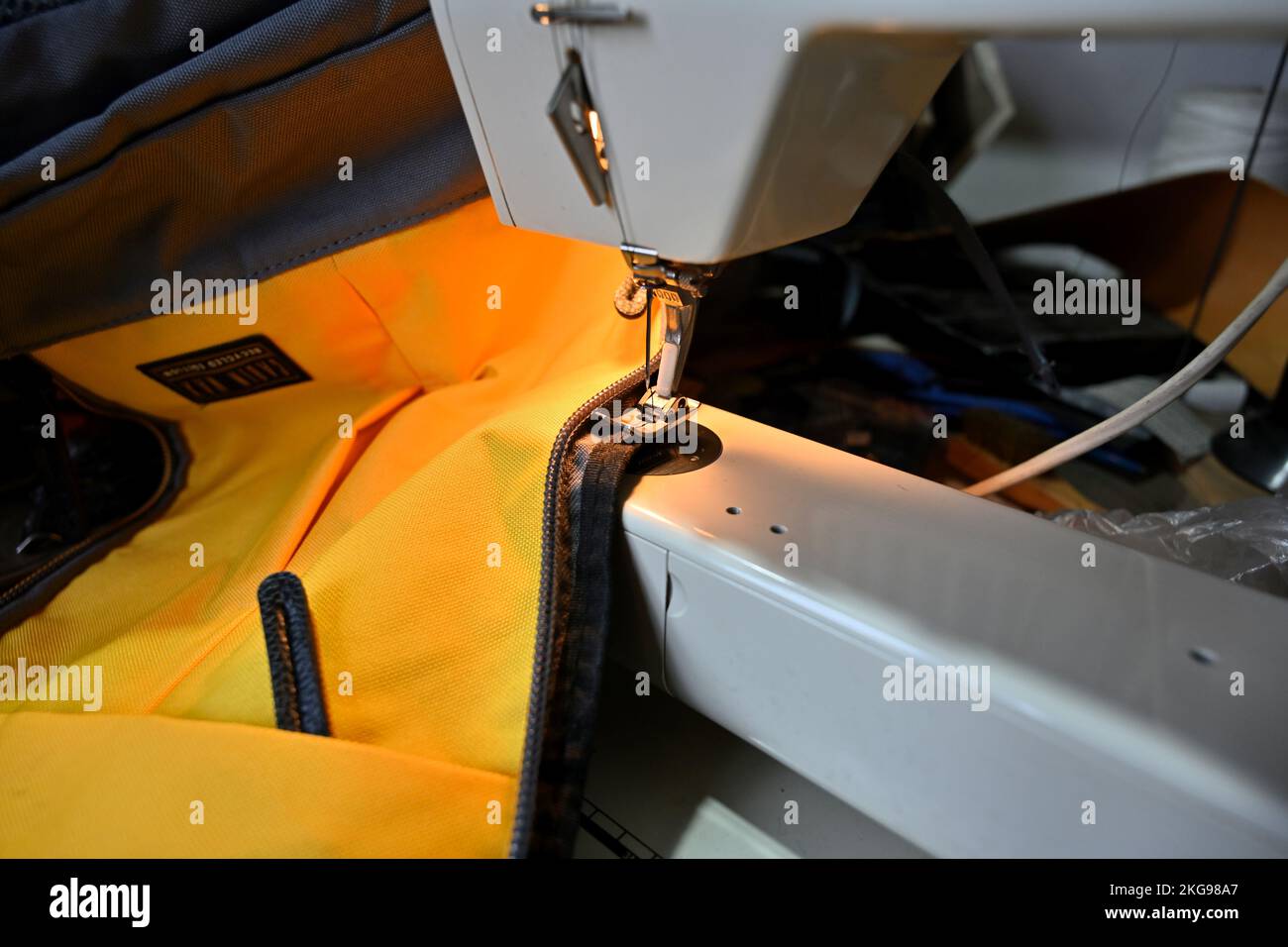 Cucire a macchina elettrica lungo la cerniera lampo su materiale giallo di sacco pesante Foto Stock