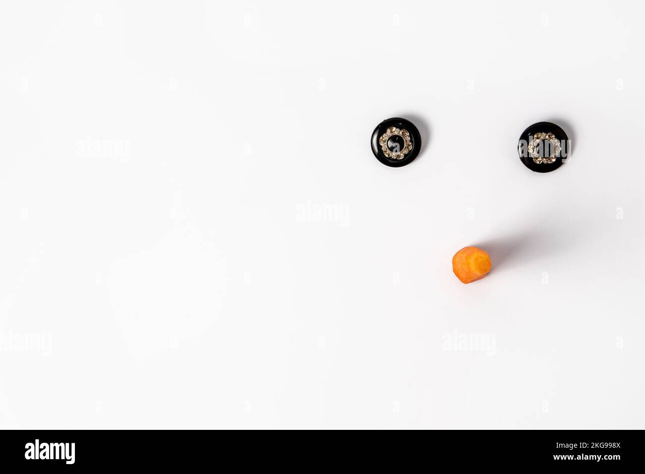 Il volto di Snowman è composto da bottoni e carota su sfondo bianco. Concetto minimo di Capodanno. Foto Stock