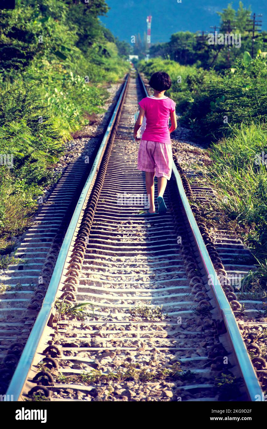 HUA HIN, THAILANDIA - 19 SETTEMBRE 2010: Una giovane ragazza tailandese cammina lungo un binario ferroviario che trasporta un pacco avvolto Foto Stock