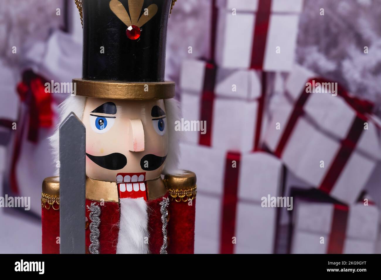 Un nutcracker di Natale in legno vicino davanti ai regali con fuoco sul volto del nutcracker Foto Stock