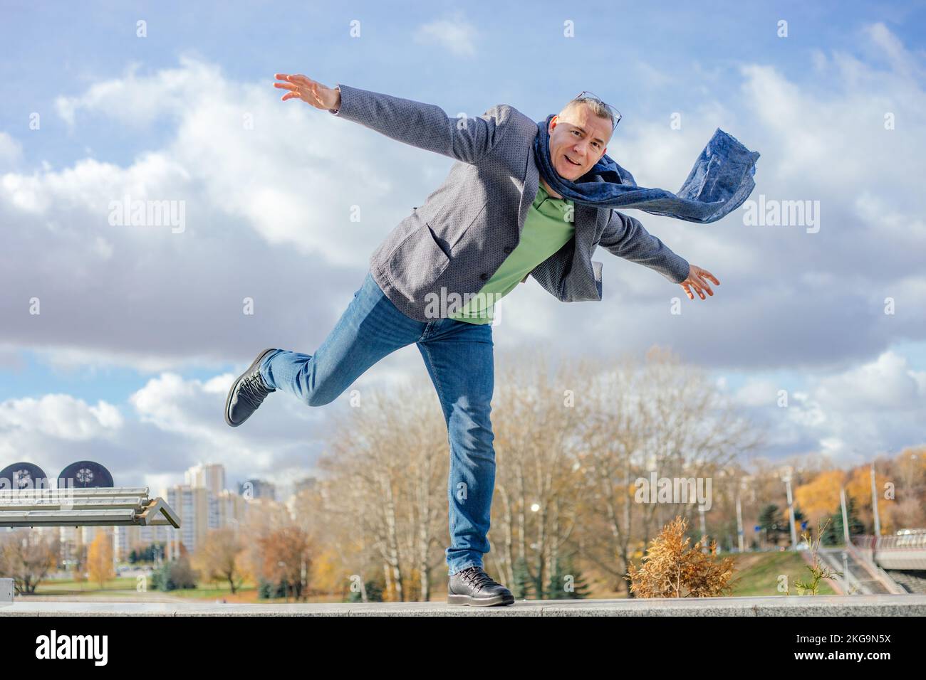 Spensierato, eccitato. uomo d'affari fidato e grizzled maturo in piedi su una gamba con la gamba sollevata e le braccia levitating sul bordo Foto Stock