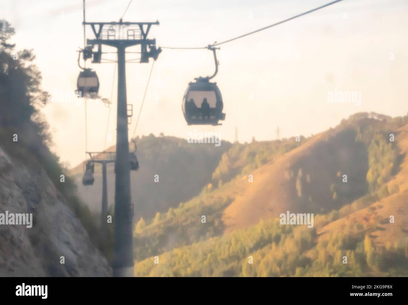 Tram aereo sfocato. Ropeway fuori fuoco con le montagne sullo sfondo. Funiviari Foto Stock