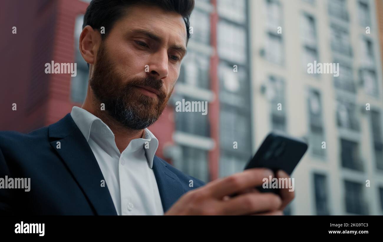 Uomo d'affari maschile SMS messaggi sul cellulare chatting online ricerca informazioni leggere notifica caucasian 30s uomo freelance lavoro in città con Foto Stock
