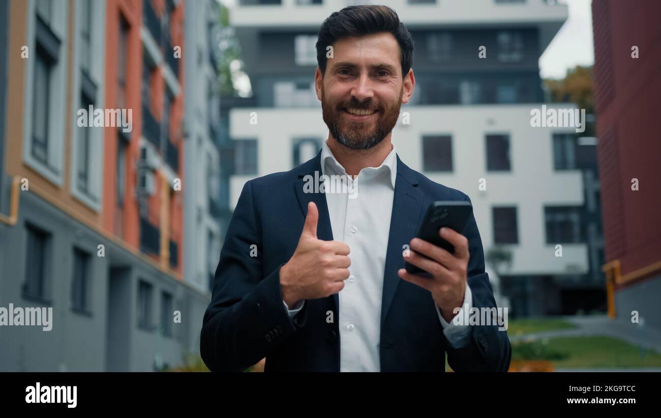 Uomo d'affari di successo caucasico uomo barbuto dipendente manager utilizzare internet città wifi chat messaggi on-line punto dito sul moderno telefono fare Foto Stock