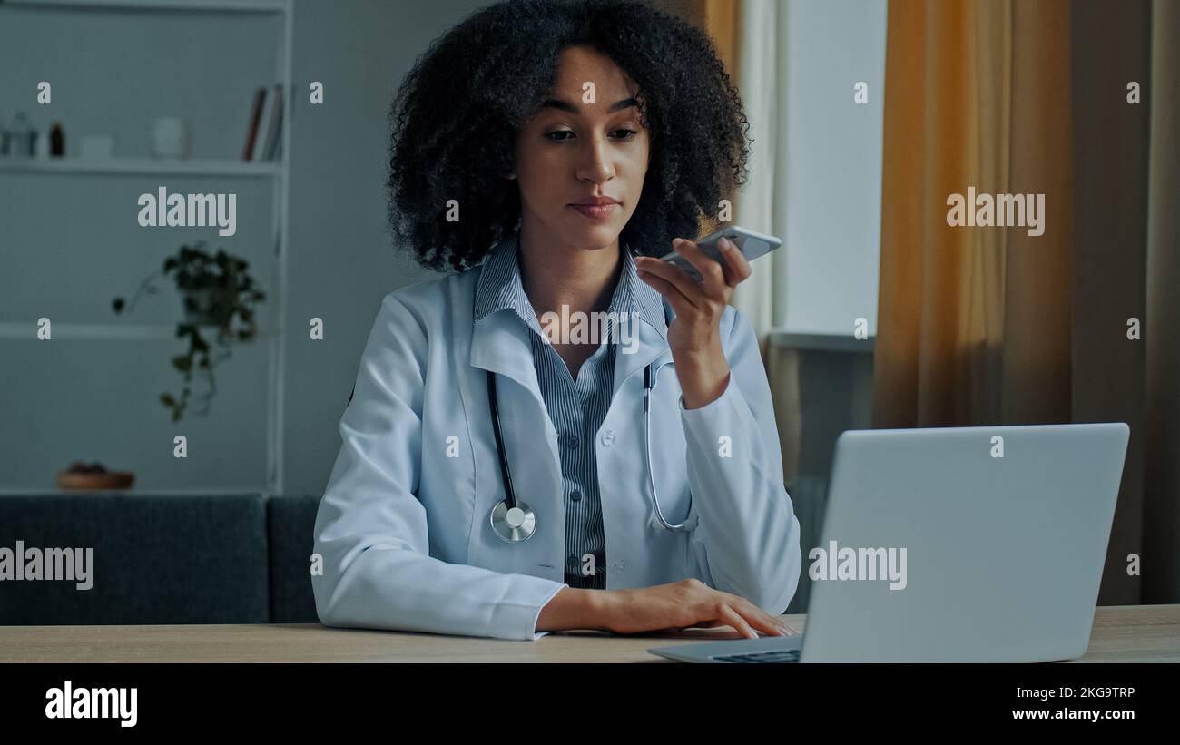 African American etnia medico donna terapista record online voice message audio medico consultazione utilizzare vivavoce forte wireless chatting virtuale Foto Stock