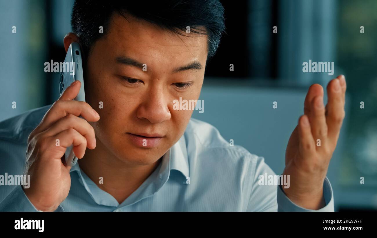 Insoddisfatto cliente uomo d'affari maschio infastidito asiatico coreano arrabbiato uomo parlare telefono cellulare ha fraintendimento problemi lamentele con il cliente risolvere Foto Stock