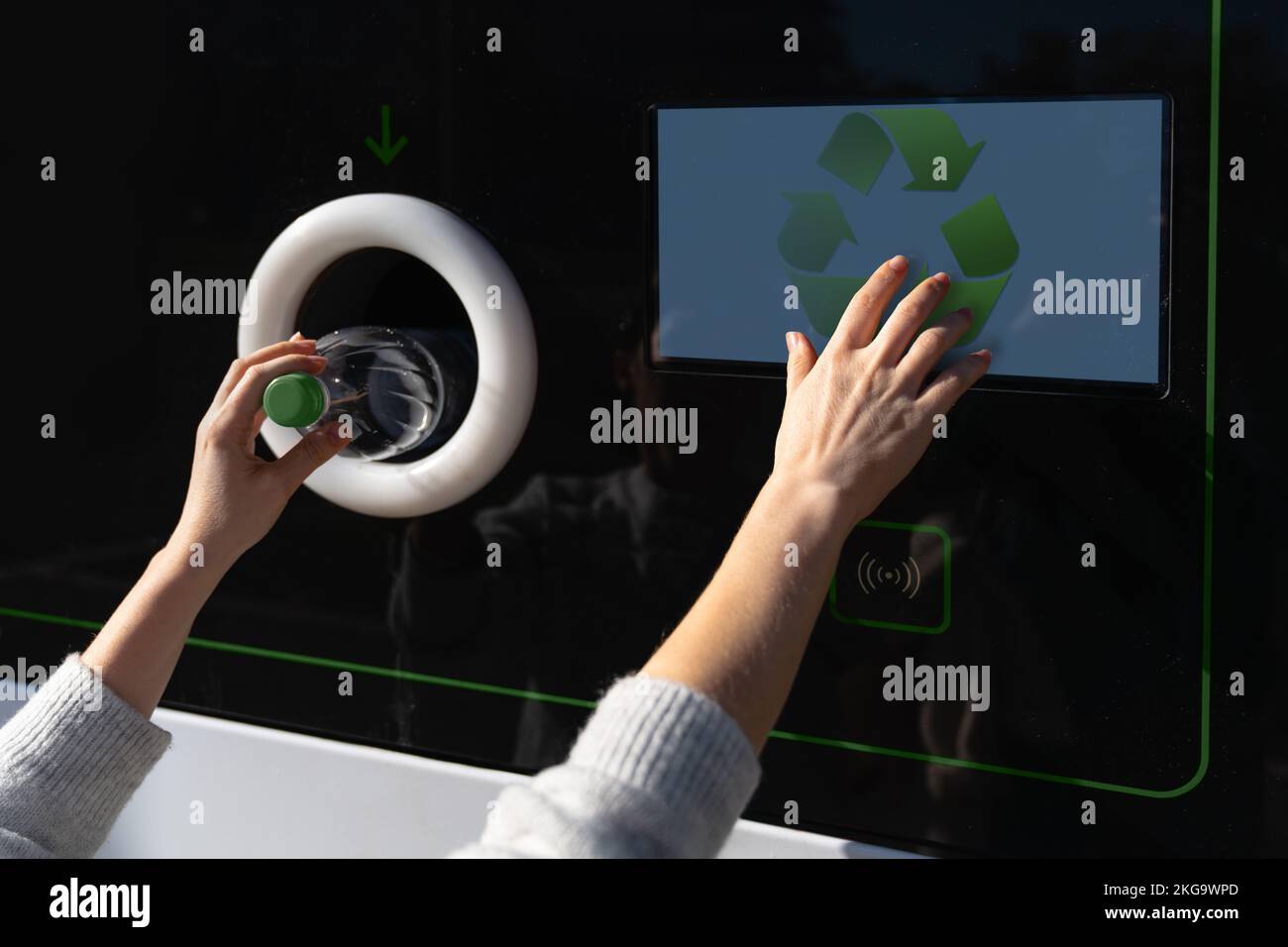 Donna utilizza una macchina self-service per ricevere bottiglie di plastica usate e lattine su una strada cittadina Foto Stock