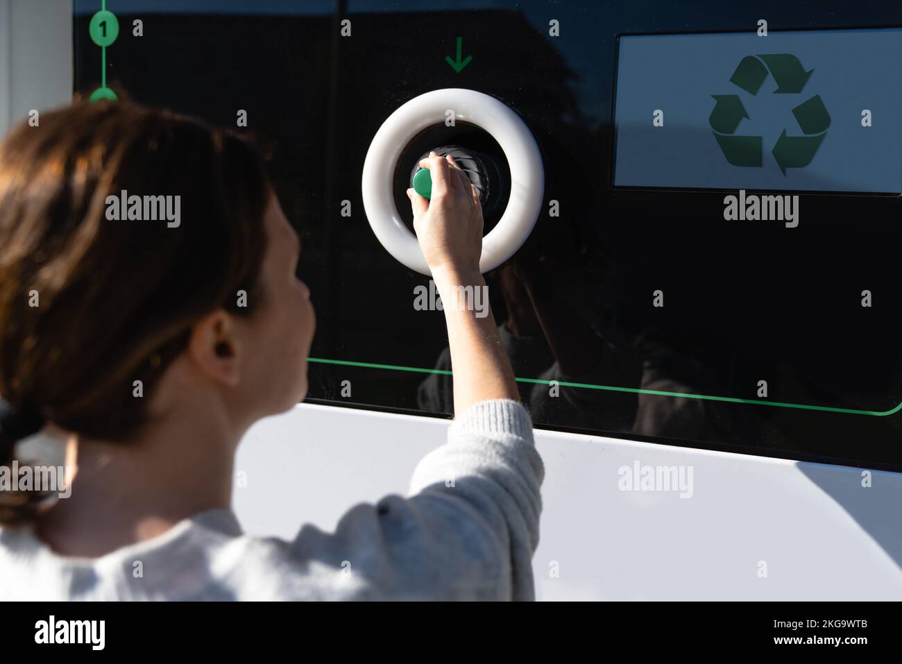 Donna utilizza una macchina self-service per ricevere bottiglie di plastica usate e lattine su una strada cittadina Foto Stock