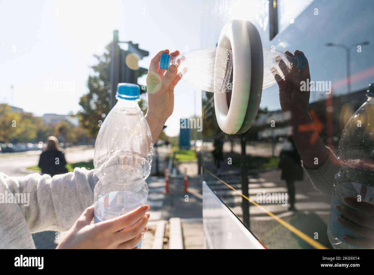 Donna utilizza una macchina self-service per ricevere bottiglie di plastica usate e lattine su una strada cittadina Foto Stock