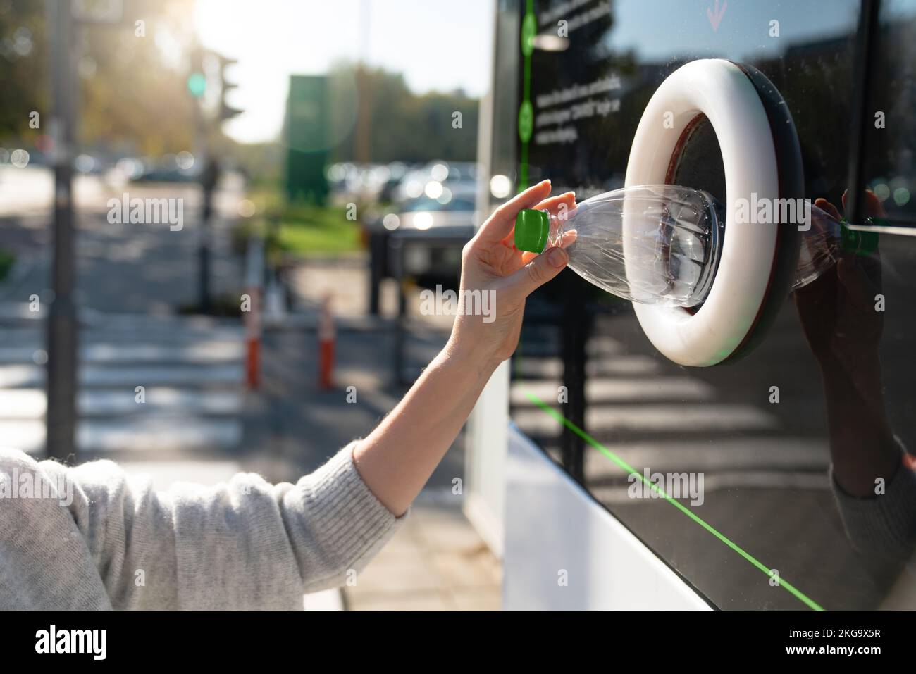 Donna utilizza una macchina self-service per ricevere bottiglie di plastica usate e lattine su una strada cittadina Foto Stock