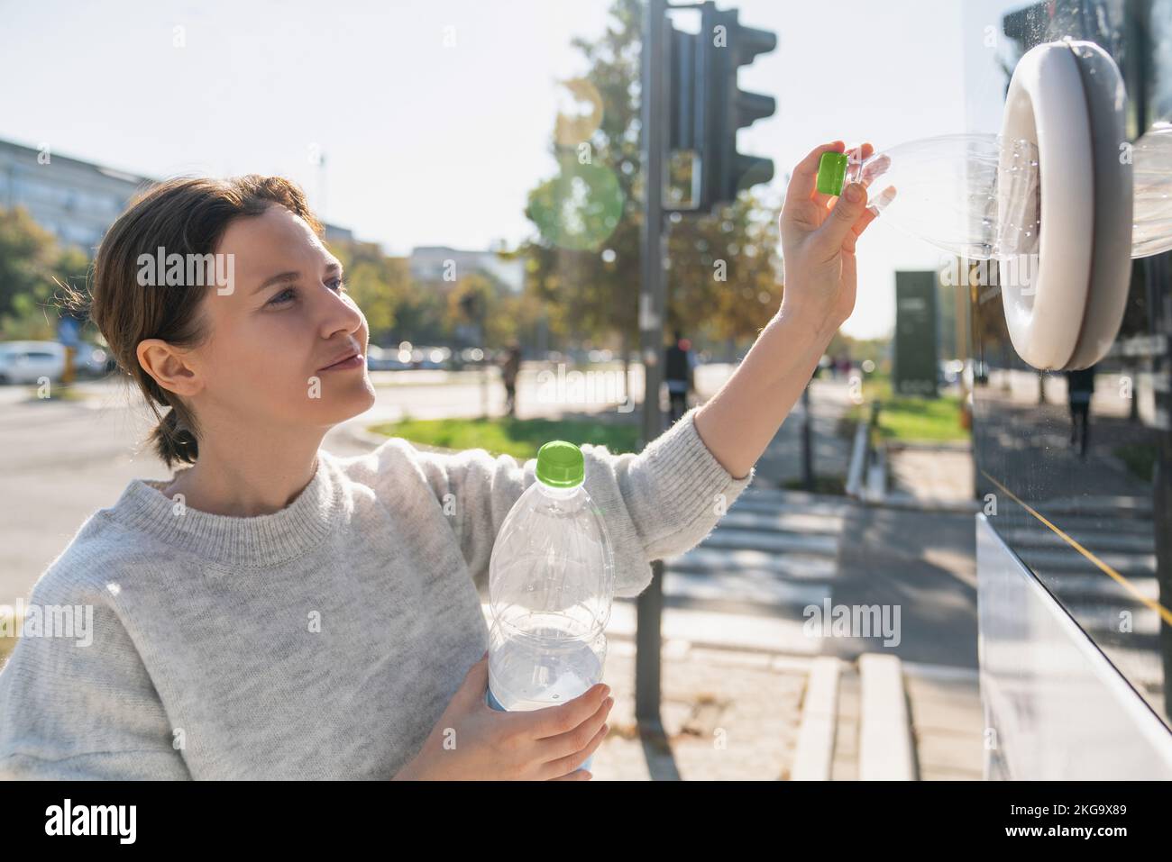 Donna utilizza una macchina self-service per ricevere bottiglie di plastica usate e lattine su una strada cittadina Foto Stock