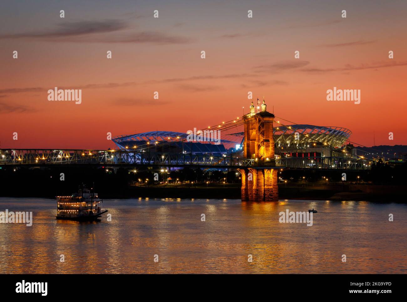 John A Roebling Suspension Bridge al tramonto. Paul Brown Stadium, Paycor Stadium, sede della squadra di football dei Cincinnati Bengals, sullo sfondo. Bella Foto Stock