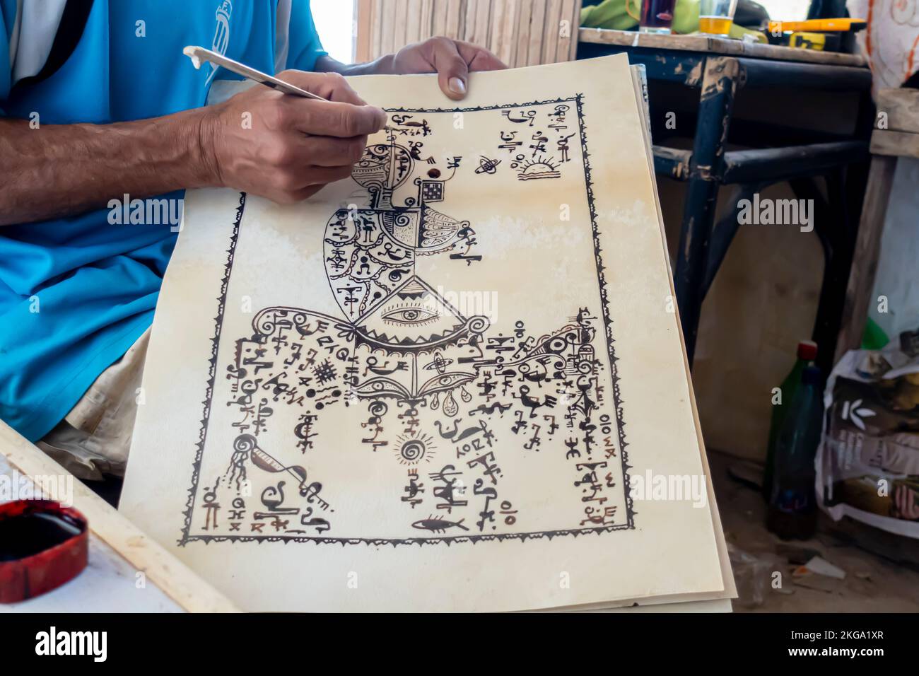 Cassetto berbero pittura tradizionale berbero simboli su carta con un bastone; inchiostro nero. Mano di cassetto artigianale berbero disegno segni berberberi, quadri. Foto Stock