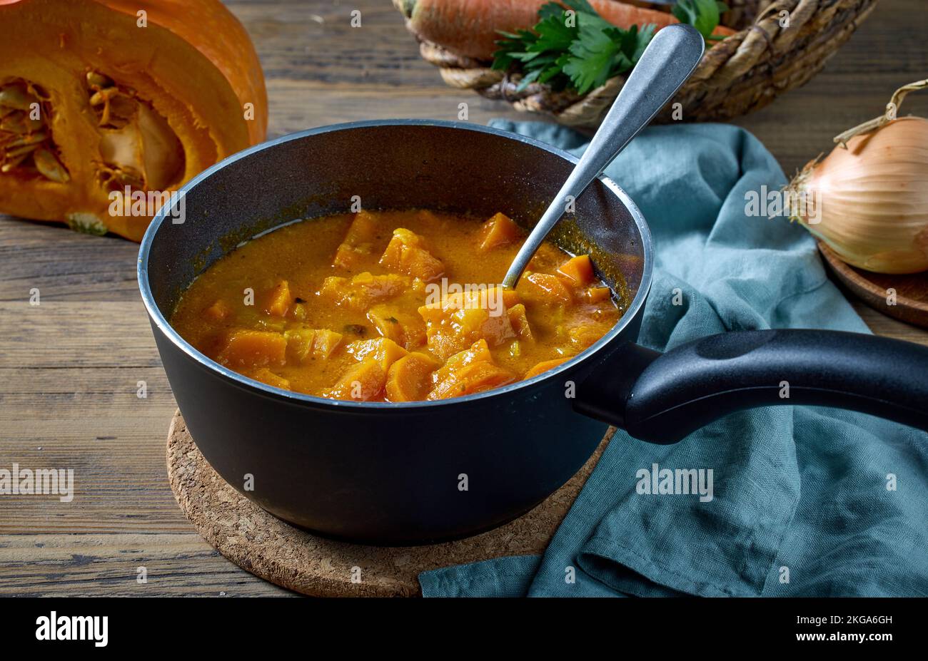 stufato di zucca e carote in una pentola da cucina sul tavolo da cucina rustico. processo di preparazione di una sana zuppa di crema di zucca Foto Stock