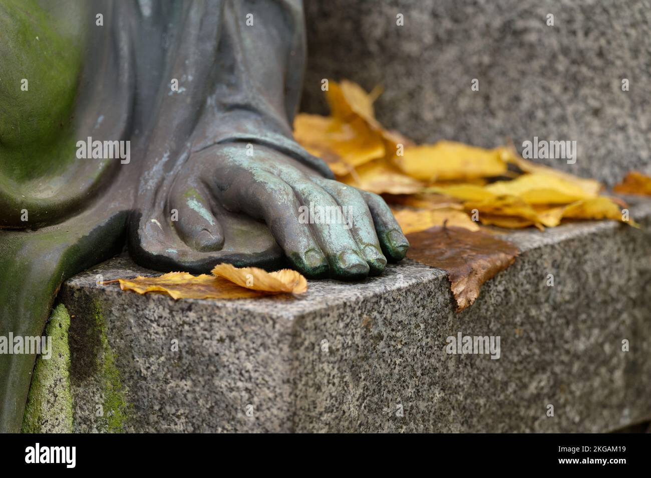 la mano di un angelo figura su una pietra con autunno lascia in un cimitero Foto Stock