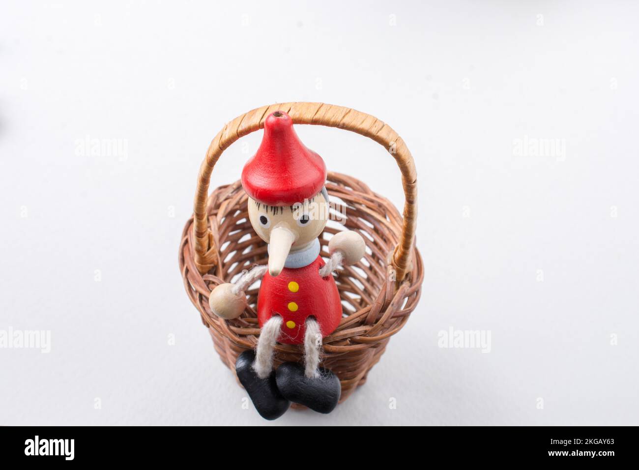 Giocattolo Pinochio figurina seduta in un cesto di paglia Foto Stock
