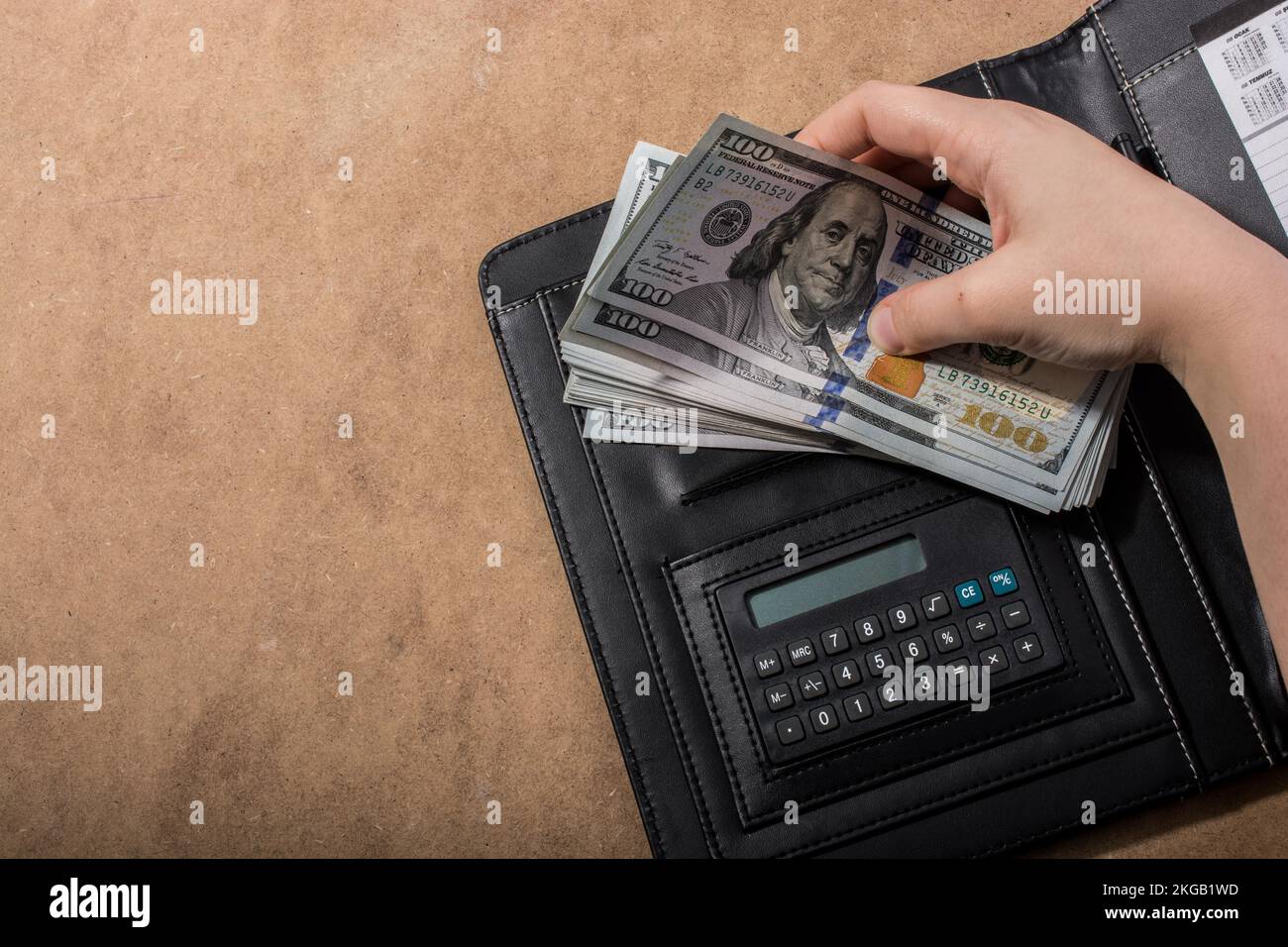 Mano azienda dollaro americano banconote accanto a una calcolatrice Foto Stock