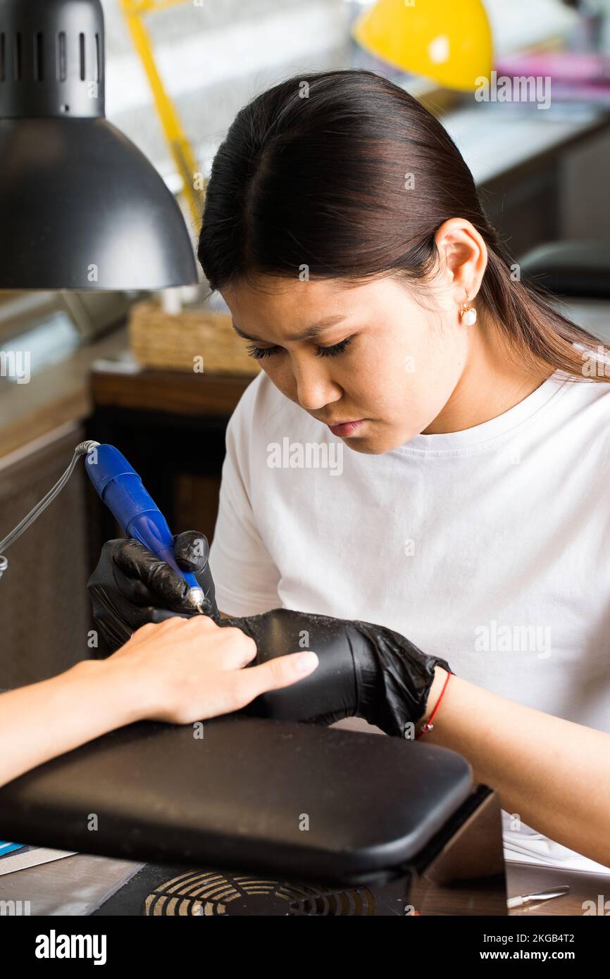 Un maestro di manicure fa una manicure hardware per un cliente in un salone di bellezza. Industria di bellezza. Foto Stock