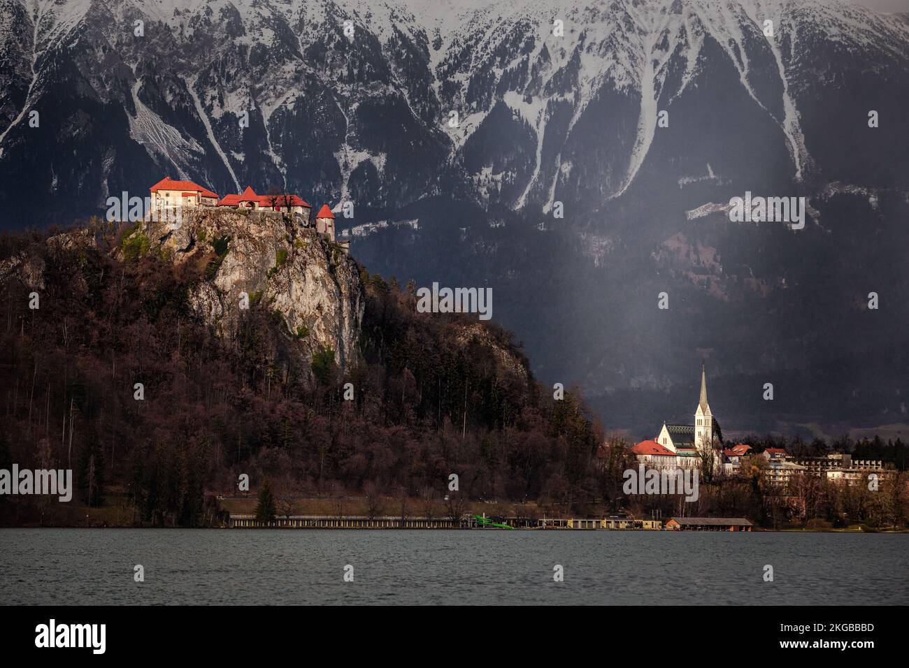Bled, Slovenia - St Chiesa Parrocchiale di Martin e Castello di Bled (Blejski Grad) con le Alpi Giulie sullo sfondo in un pomeriggio invernale soleggiato in Slovenia Foto Stock