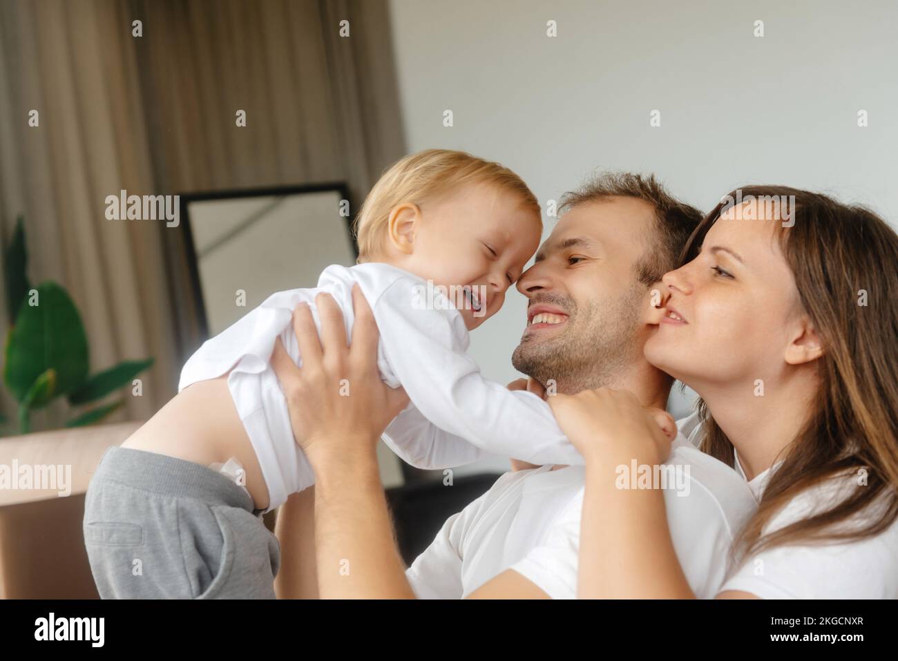 un padre sorridente che tiene un bambino in braccio alla madre accanto a lui. Stile di vita familiare felice. Bambino sorridente e ridente. Un'infanzia felice e un sano Foto Stock