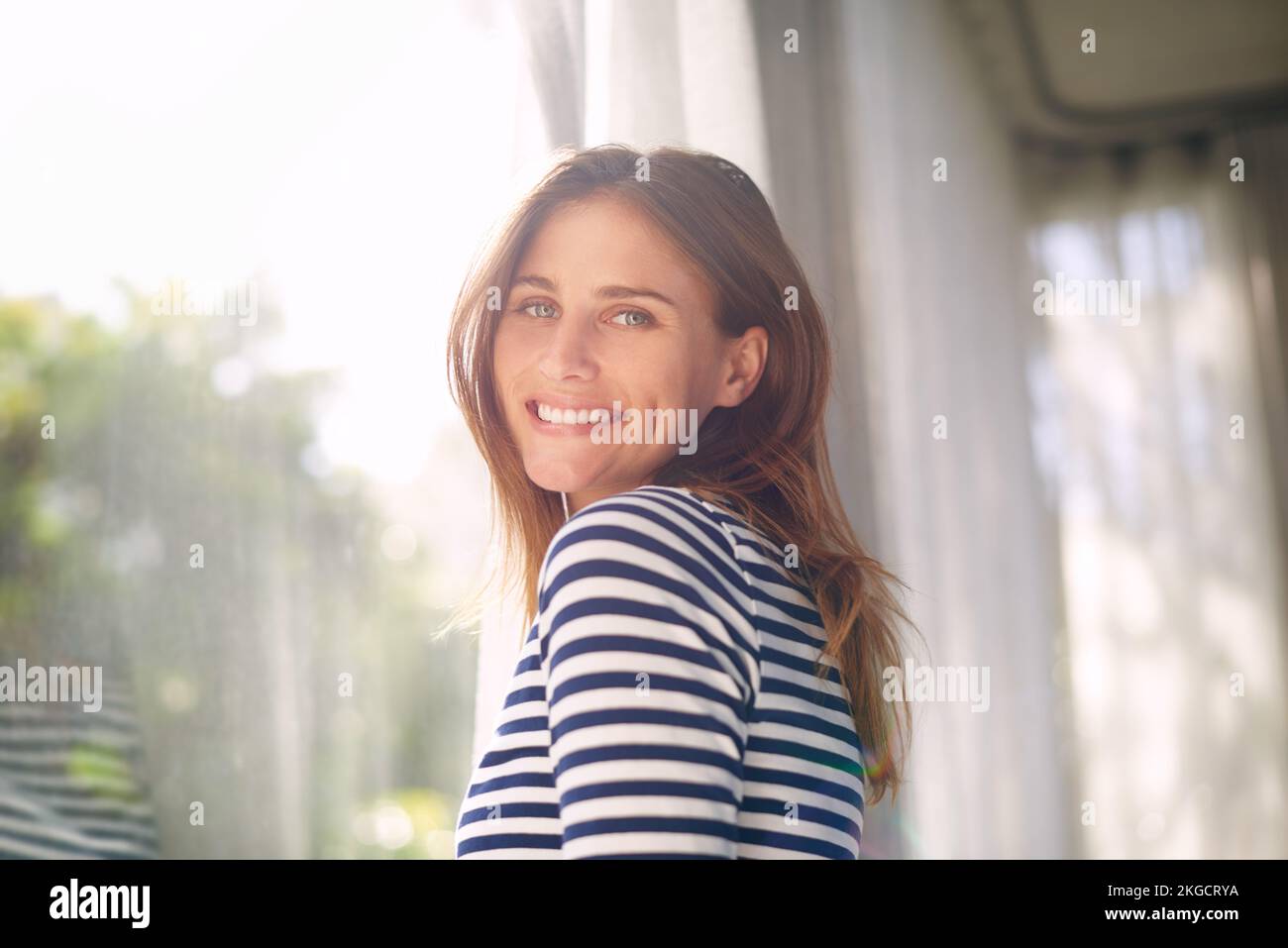 Mi piace questo momento della giornata. una bella giovane donna bagnata dalla luce della finestra. Foto Stock