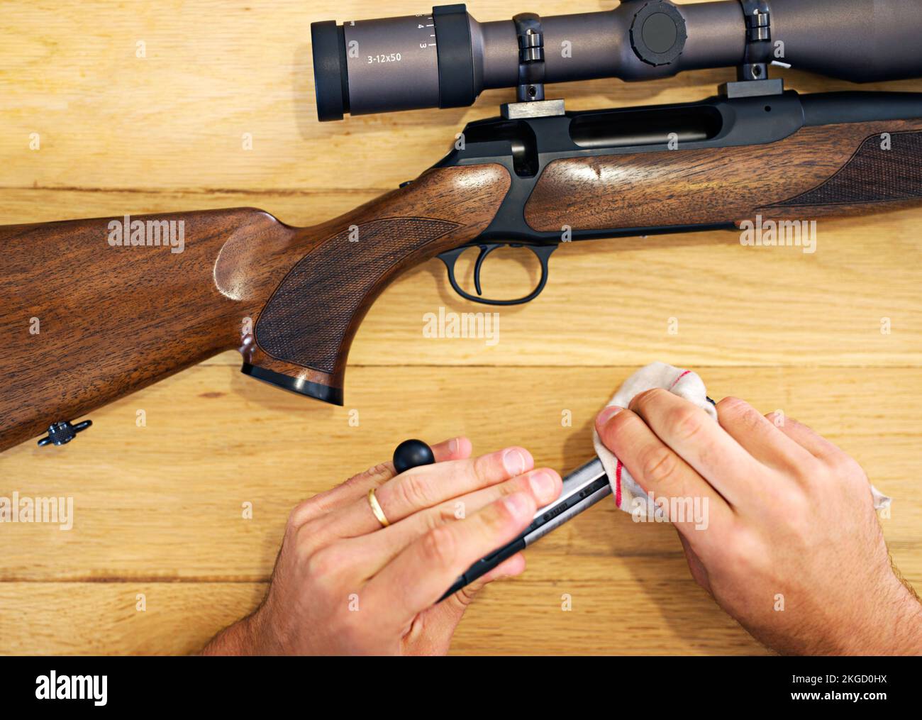 La manutenzione regolare è essenziale per ogni proprietario di pistola. Vista ritagliata di un uomo che pulisce il suo fucile. Foto Stock