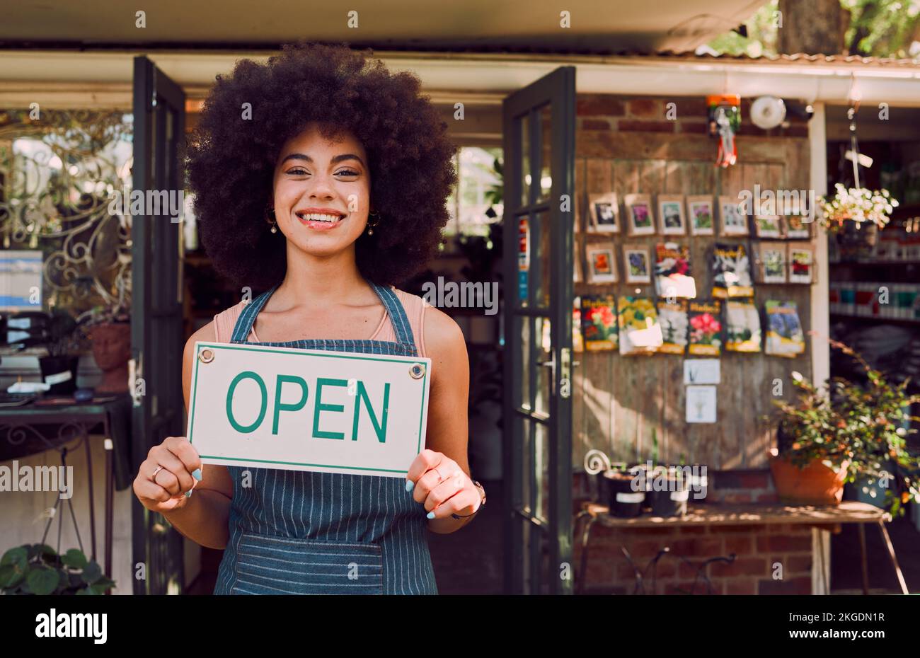 Open segno, donna nera e giardino proprietario di un piccolo business manager ritratto felice. Sorridi un imprenditore di un negozio al dettaglio con shopping di benvenuto Foto Stock