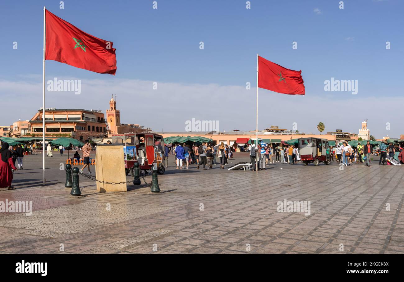 La piazza jamma el fna è la piazza principale di marrakech marocco circondata da negozi, bancarelle, bar e ristoranti, la bandiera moroccon domina. Foto Stock
