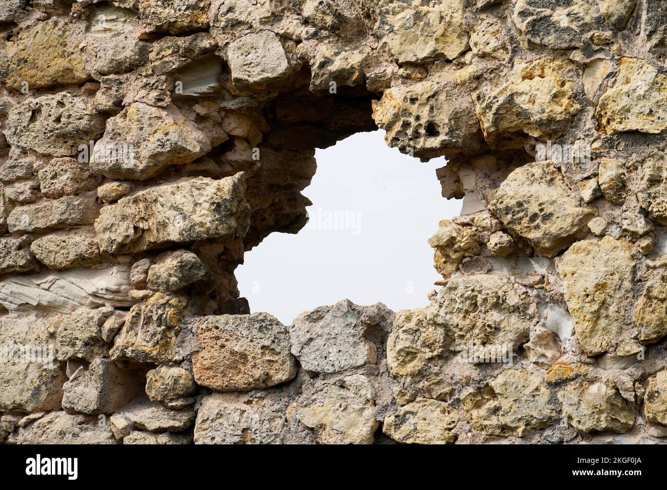 Vecchio muro di pietra di un castello con vista sul cielo. Muro difensivo con scappatoia. Foto Stock