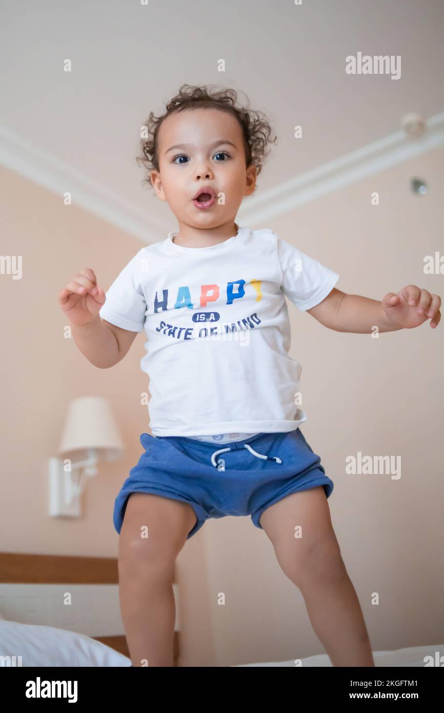 Divertente bambino felice che salta sul letto dei genitori nella camera da letto principale Foto Stock