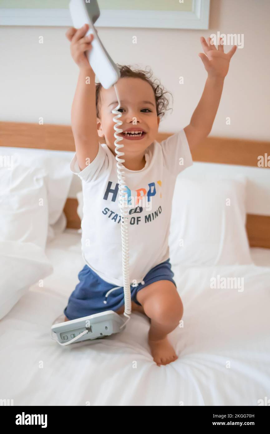 Un bambino felice chiama con un telefono a pressione in camera Foto Stock