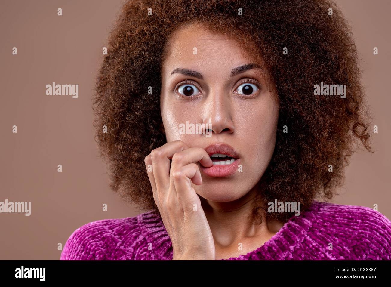 Giovane donna dai capelli scuri che guarda spaventata Foto Stock