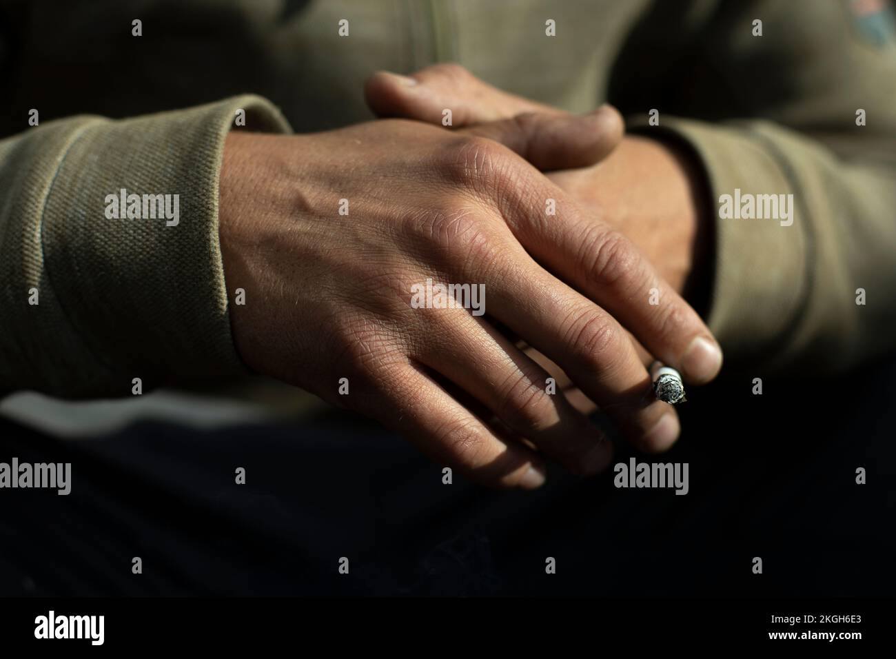 Mano nel dettaglio. Sigaretta inserita tra le confezioni. Luce sul retro della spazzola. Foto Stock