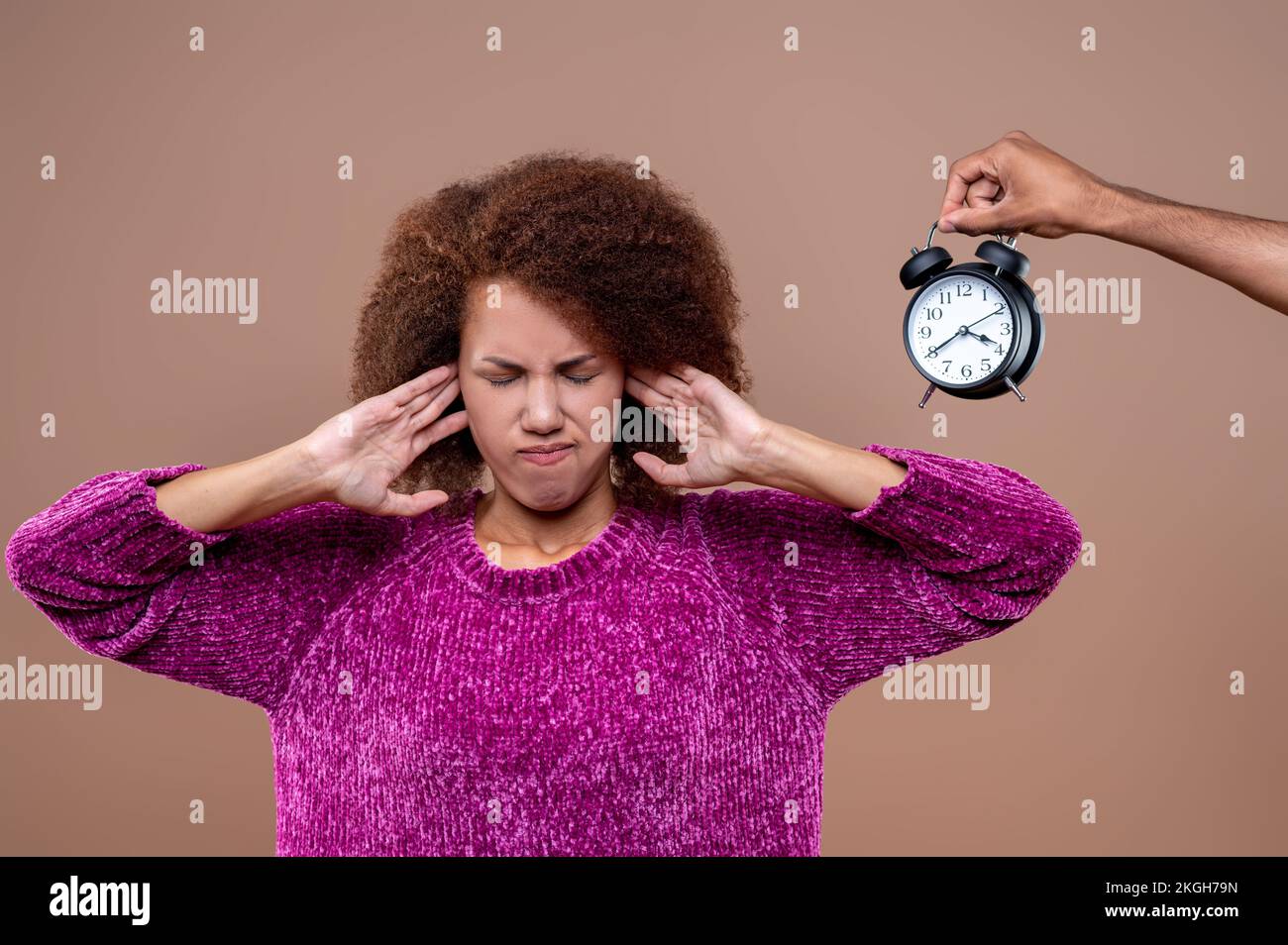 Giovane donna che chiude le orecchie dal suono dell'orologio Foto stock -  Alamy