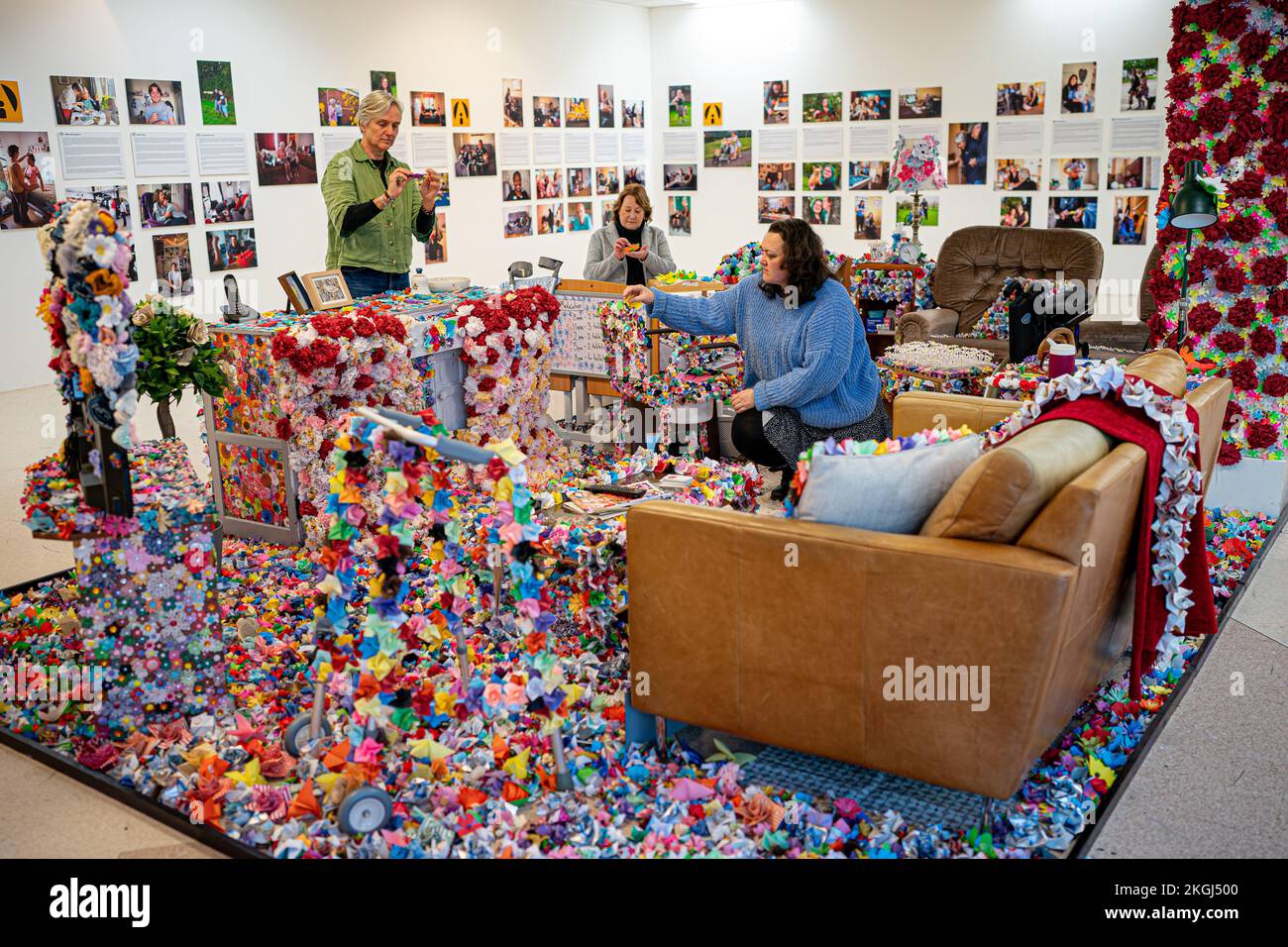 Un'installazione di fiori creato da Carer Carina Andrews (nella foto a destra) per celebrare la Giornata dei diritti di Carers il 24 novembre, presso il centro commerciale Galleries di Broadmead, Bristol. Il pezzo utilizza 40.138 fiori di carta, ognuno dei quali rappresenta un accompagnatore non retribuito nella zona di Bristol, con i fiori realizzati da accompagnatori e volontari nel corso del 2022 e copre un mock up del salotto del genitore di Carina. Data immagine: Mercoledì 23 novembre 2022. Foto Stock