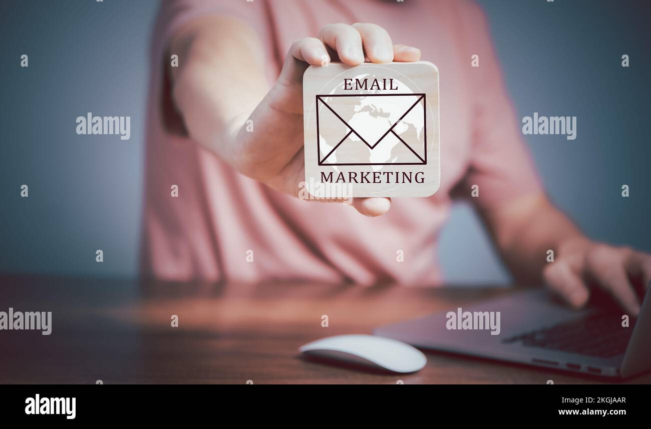 Concetto di vendita del email, uomo che usa il calcolatore del laptop e che tiene la piastra di legno con l'icona del email e il testo di vendita del email di scrittura. Foto Stock