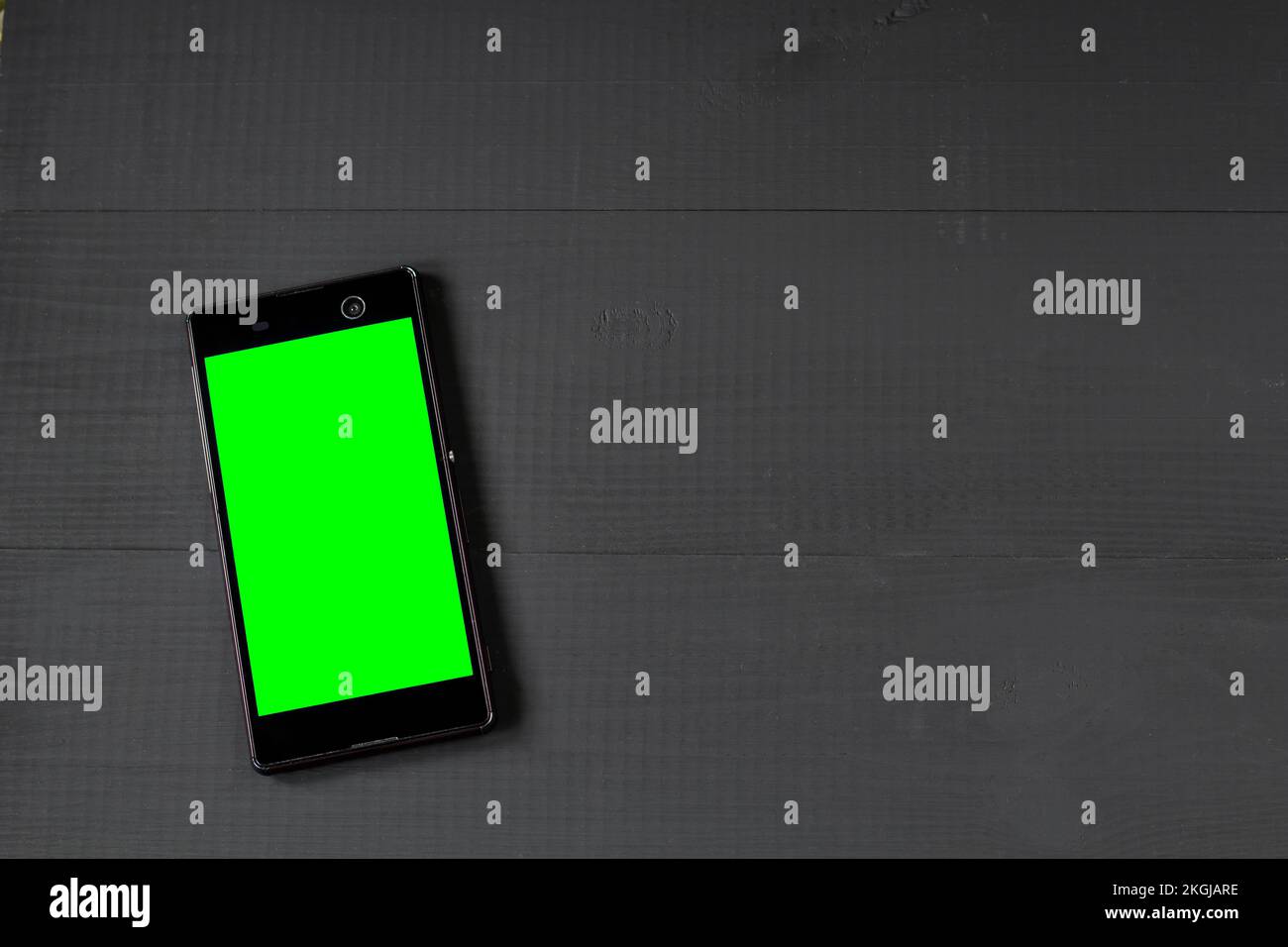 smartphone con schermo verde su tavolo di legno Foto Stock