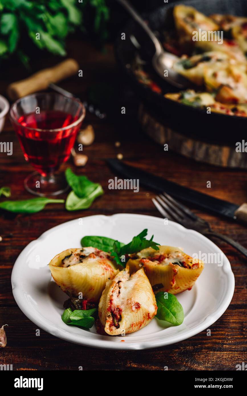 Conchiglie di jumbo al forno farcite con manzo macinato, spinaci e formaggio su piatto bianco Foto Stock