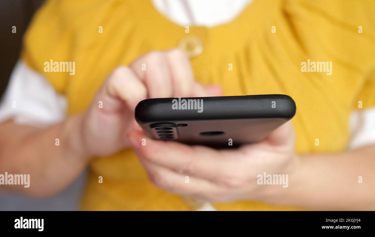 Mano di donna anziana che scrive il messaggio ad un amico sullo smartphone Foto Stock
