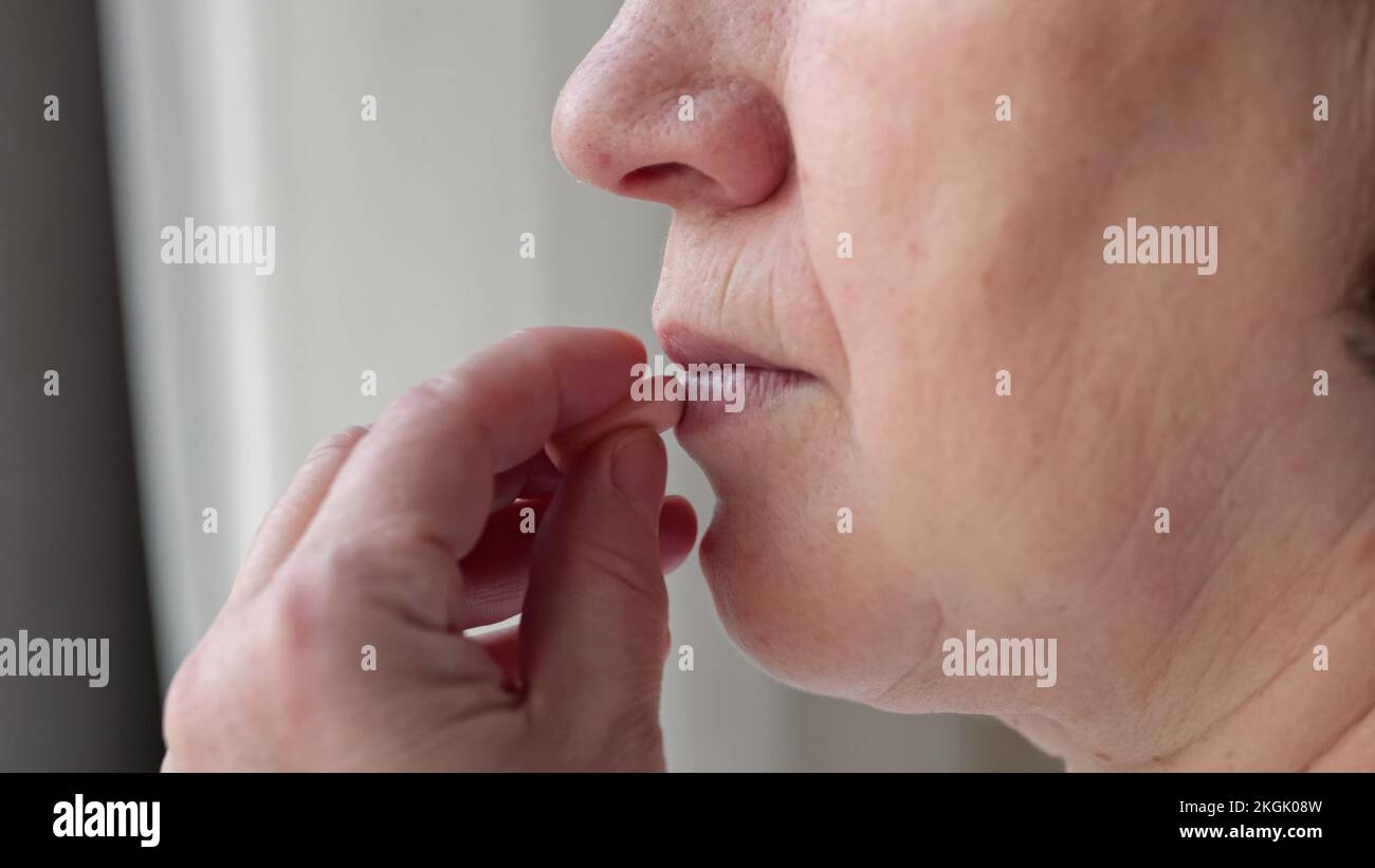 Donna prende antidolorifici per alleviare il mal di testa acqua potabile Foto Stock