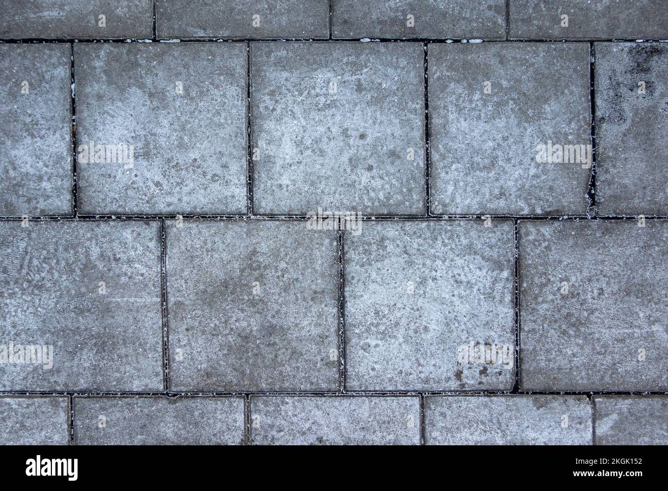 Sale spalmato su pavimenti ghiacciati in città. Mattoni coperti con macchie di sale. Marciapiede scivoloso in inverno. Foto Stock