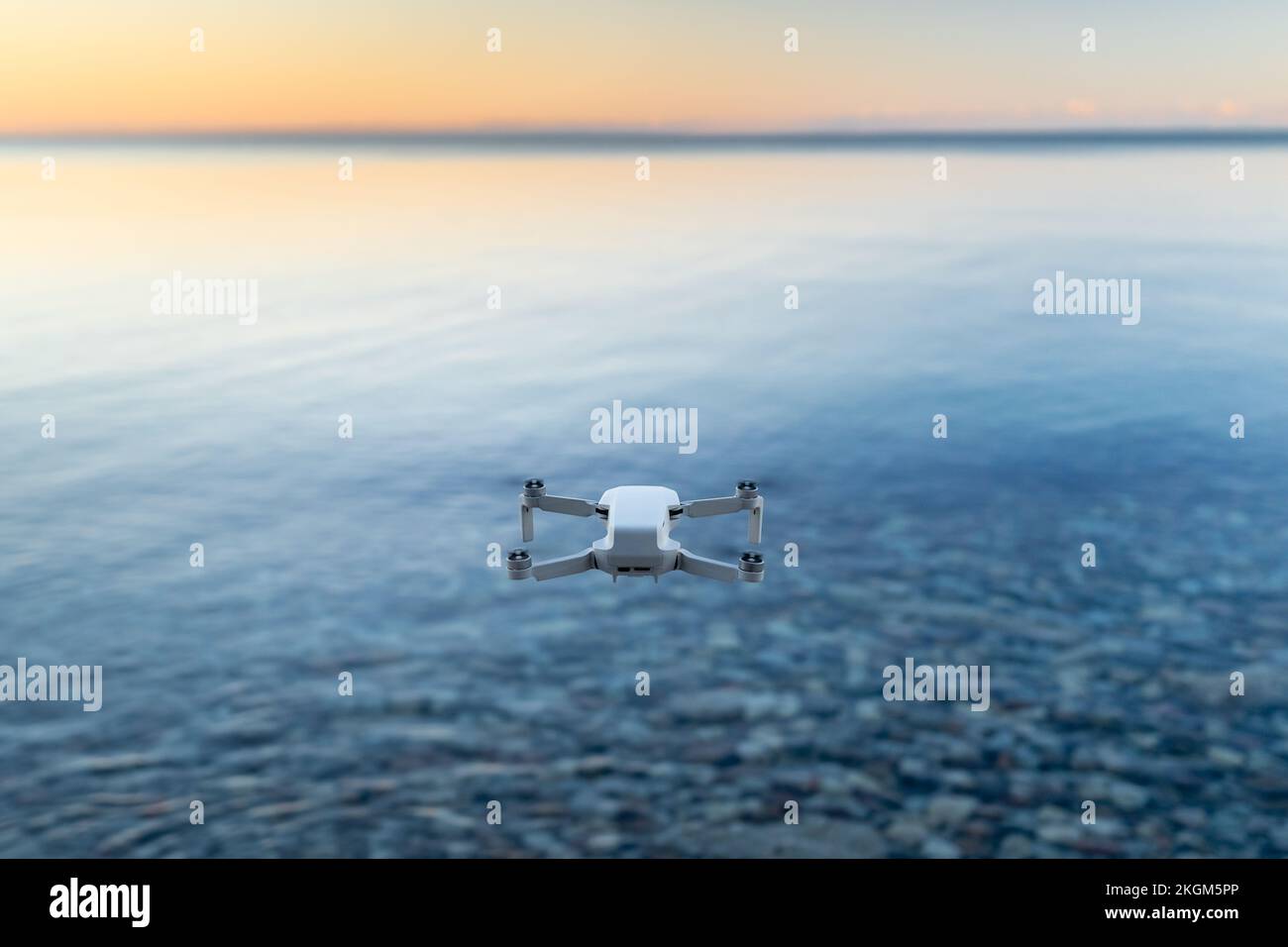 Un micro drone si avvolse nell'aria sopra un corpo d'acqua Foto Stock