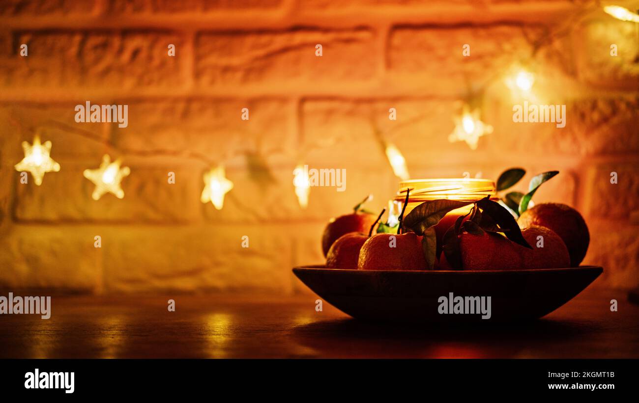 Natale candele sera sfondo scuro banner web. Citrus candela per le feste e succose arance su tavolo in legno cucina. Nuova casa Foto Stock