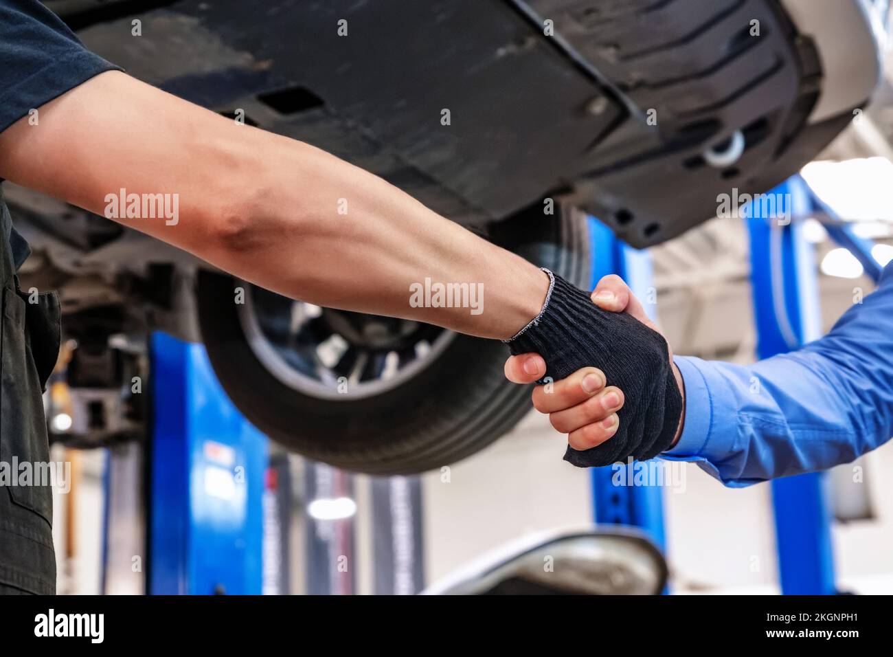 Il cliente e il meccanico addetto all'assistenza automatica si scuotono le mani. Riparazione e manutenzione dell'auto Foto Stock