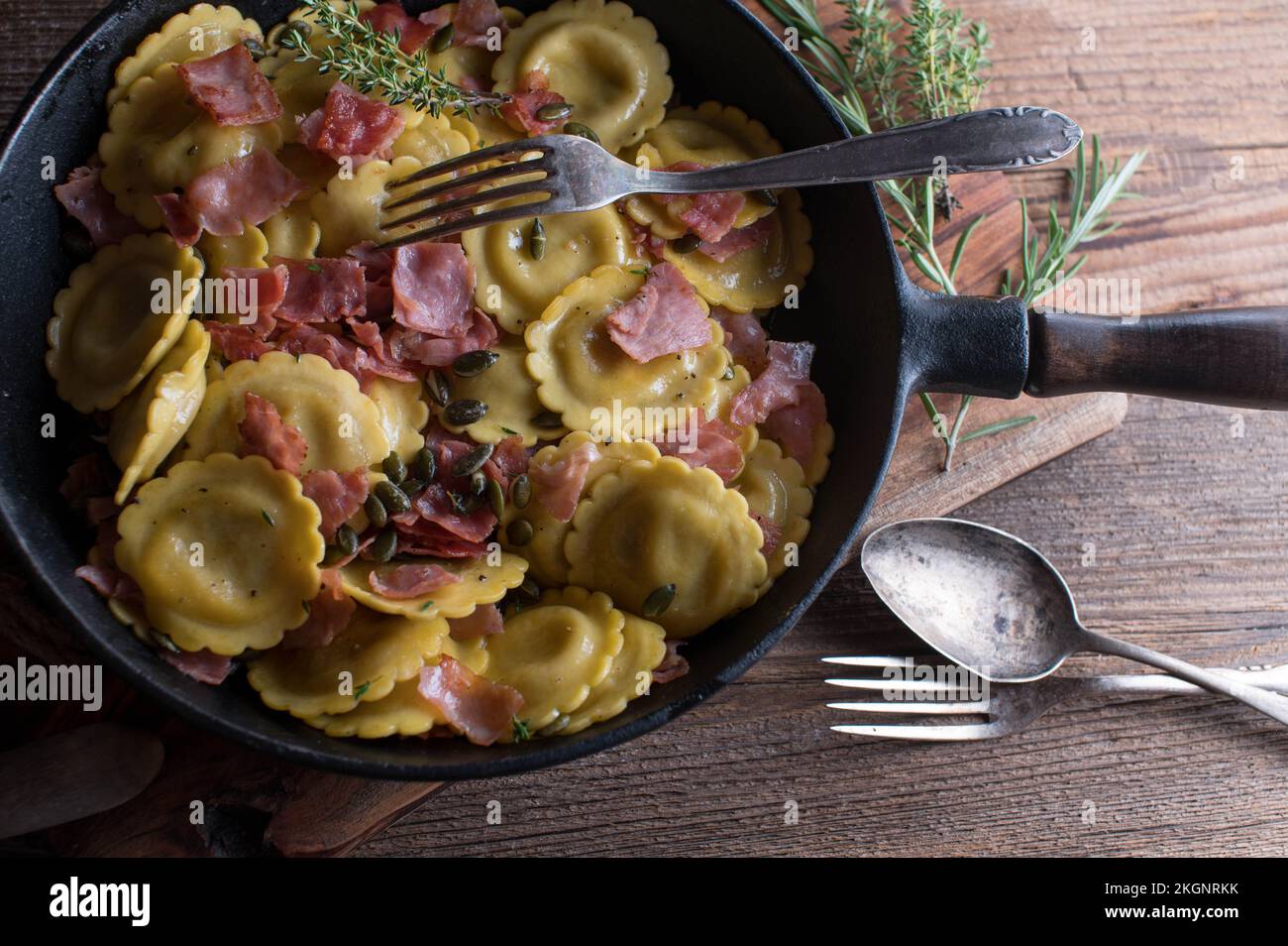 Piatto di pasta italiana con ravioli e ripieno di funghi. Cotto con burro, prosciutto, erbe e semi di zucca arrosto Foto Stock