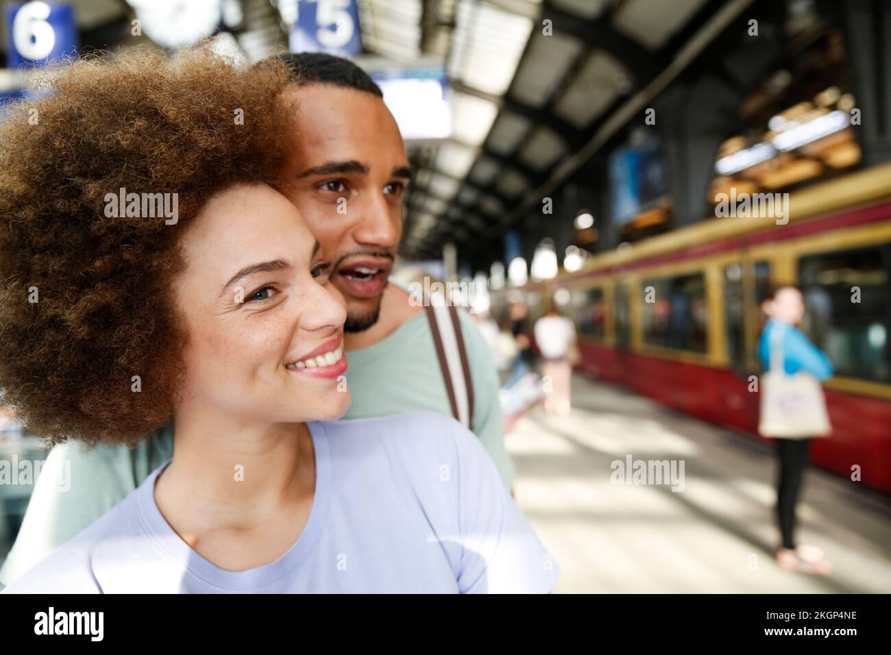 Felice coppia giovane in attesa di treni pendolari Foto Stock