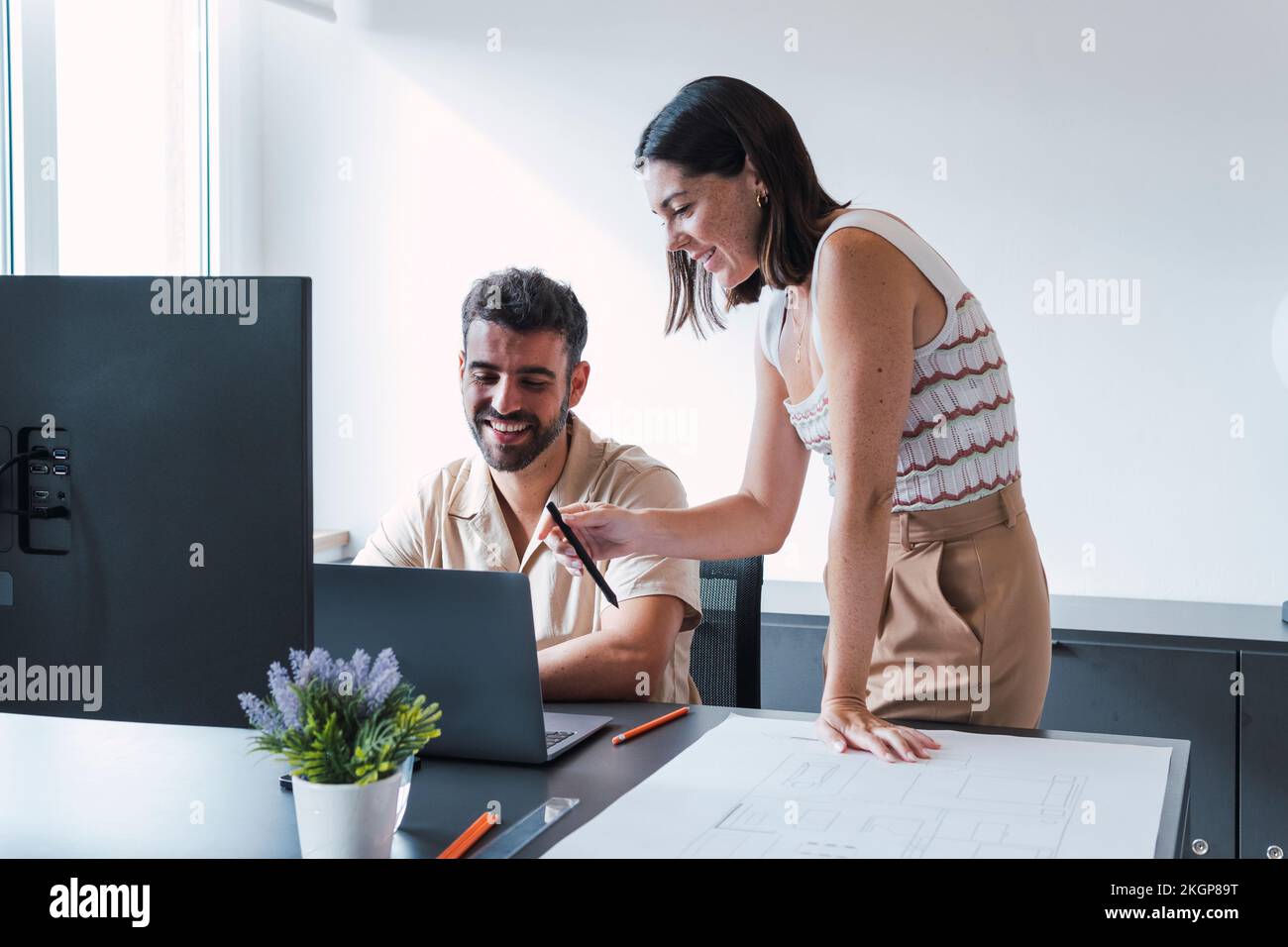 Colleghi felici di discutere sul laptop in ufficio Foto Stock
